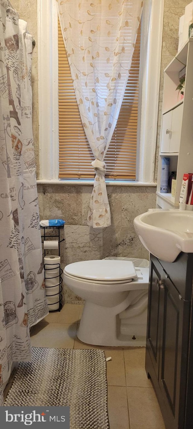 bathroom with tile patterned floors, vanity, toilet, and tile walls