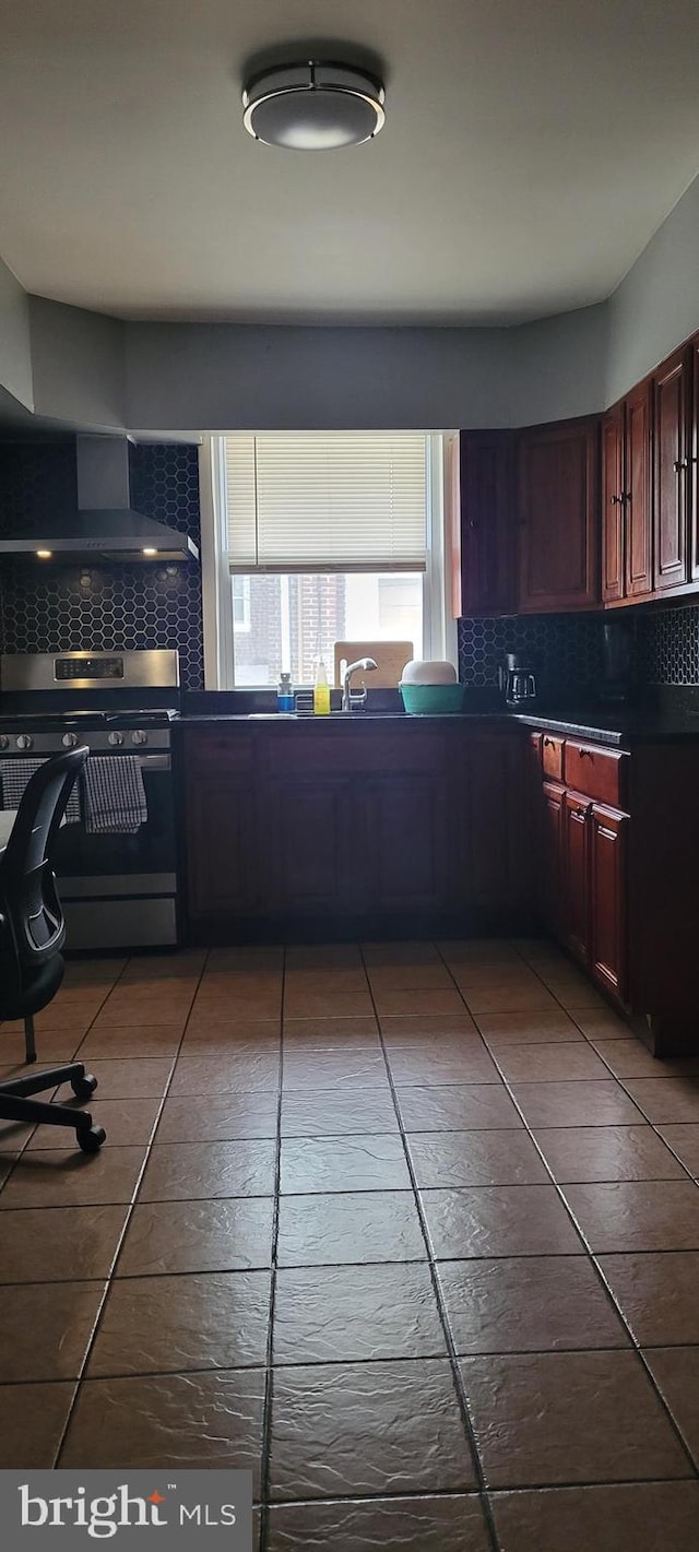 kitchen featuring wall chimney exhaust hood, stainless steel stove, sink, and backsplash