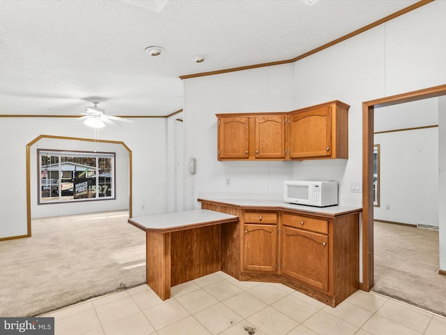 kitchen with crown molding, a textured ceiling, kitchen peninsula, ceiling fan, and light carpet