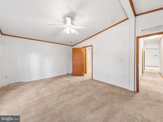 empty room with light carpet, ceiling fan, vaulted ceiling, and ornamental molding