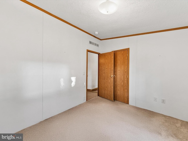 unfurnished bedroom with ornamental molding, carpet, and a textured ceiling