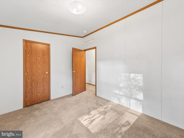 unfurnished bedroom with ornamental molding, light carpet, and a textured ceiling