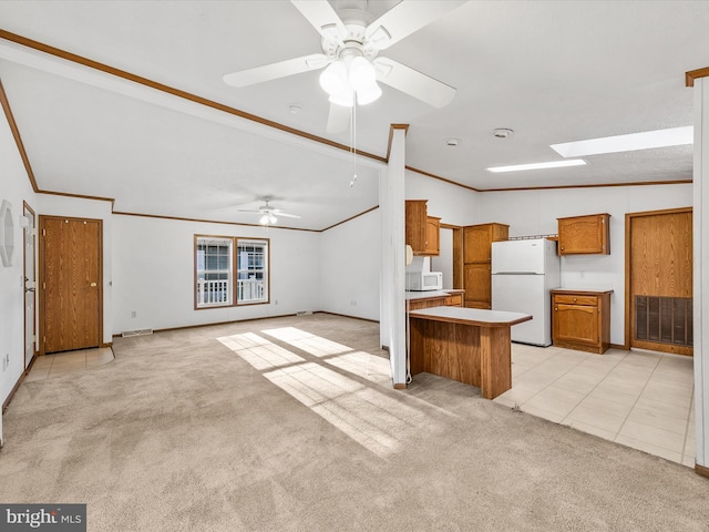 kitchen featuring white appliances, vaulted ceiling, ceiling fan, and light colored carpet