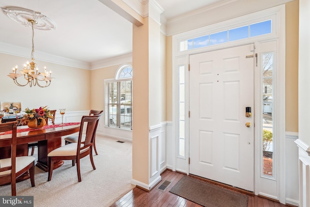 foyer entrance featuring hardwood / wood-style floors, crown molding, and a chandelier