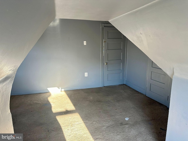 bonus room with vaulted ceiling and dark colored carpet