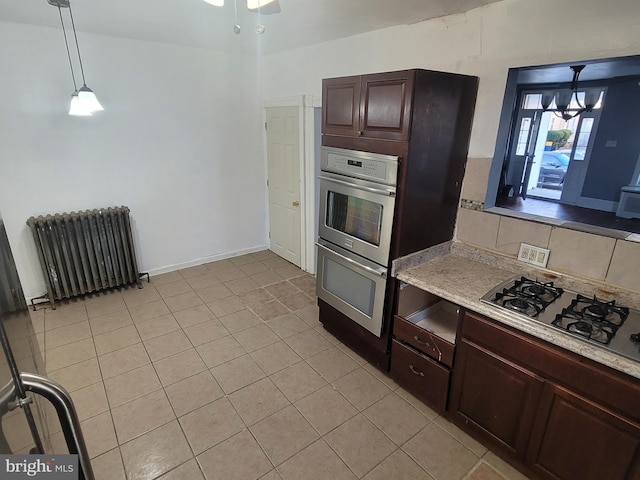 kitchen featuring gas cooktop, radiator, dark brown cabinetry, light tile patterned floors, and hanging light fixtures