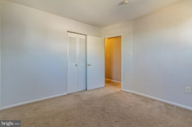 unfurnished bedroom featuring light carpet and a closet