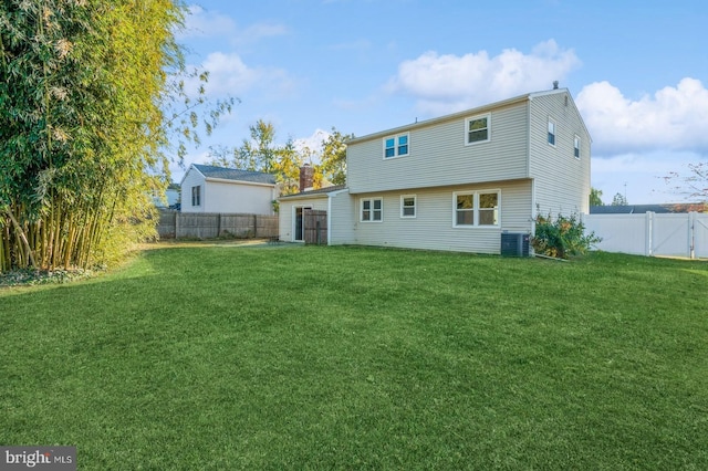 back of house featuring central AC unit and a yard