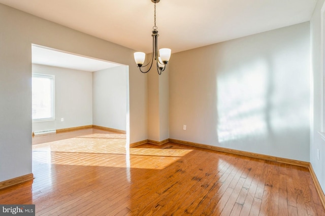 spare room with a chandelier and hardwood / wood-style flooring