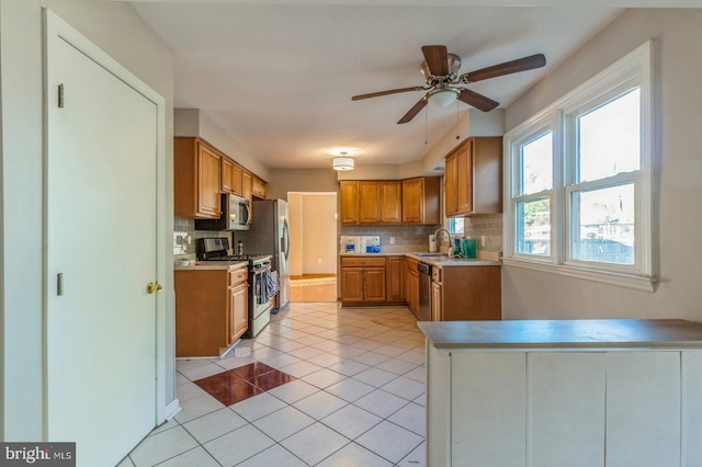 kitchen with stainless steel appliances, sink, ceiling fan, light tile patterned floors, and decorative backsplash