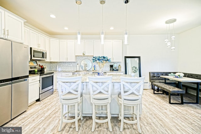 kitchen featuring a center island, white cabinets, decorative light fixtures, and stainless steel appliances