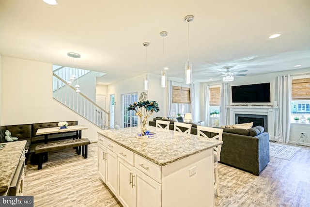 kitchen featuring white cabinetry, a kitchen bar, hanging light fixtures, light hardwood / wood-style flooring, and a center island