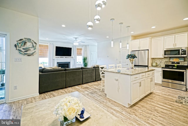 kitchen featuring white cabinets, a wealth of natural light, stainless steel appliances, and a kitchen island