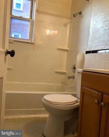 full bathroom featuring vanity, toilet, washtub / shower combination, and a wealth of natural light