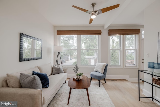 living room with beamed ceiling, ceiling fan, and light wood-type flooring