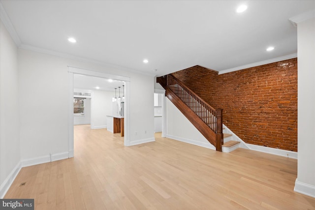 unfurnished living room featuring light hardwood / wood-style floors, ornamental molding, and brick wall