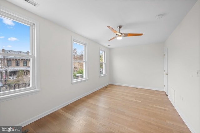 spare room with light wood-type flooring, plenty of natural light, and ceiling fan