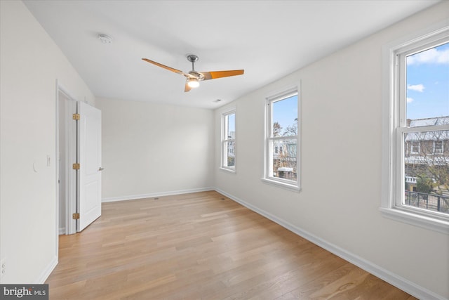 empty room featuring plenty of natural light, light hardwood / wood-style floors, and ceiling fan