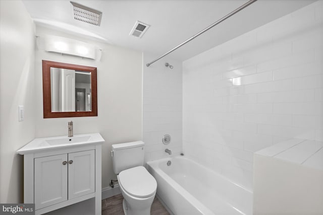 full bathroom featuring vanity, hardwood / wood-style floors, tiled shower / bath combo, and toilet