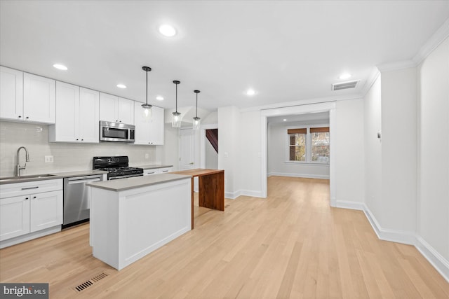 kitchen with white cabinets, hanging light fixtures, sink, and appliances with stainless steel finishes