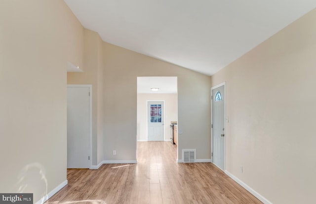 spare room featuring light hardwood / wood-style floors and vaulted ceiling