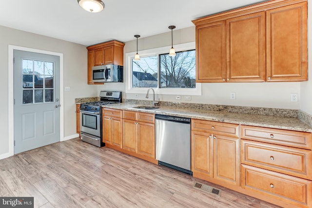 kitchen with light wood-type flooring, stainless steel appliances, a healthy amount of sunlight, and sink