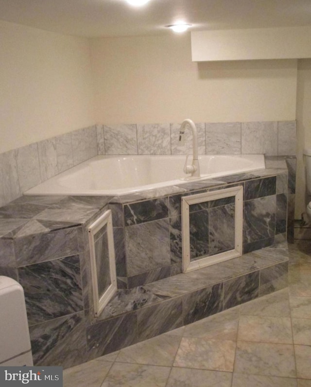 bathroom featuring tiled tub and toilet