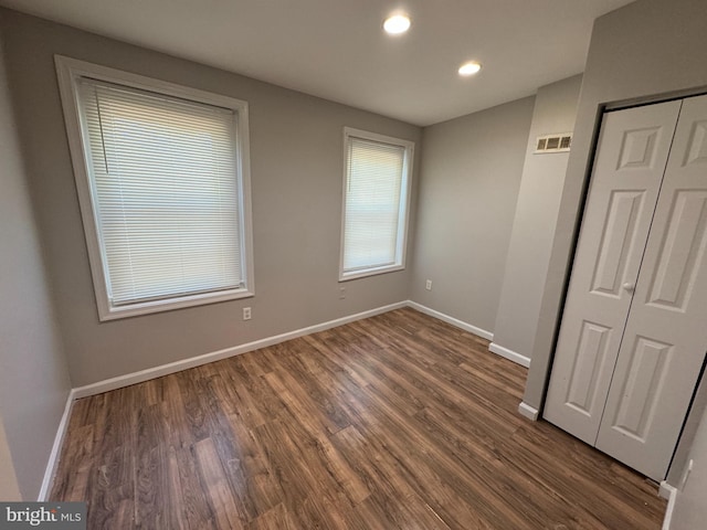 unfurnished bedroom featuring dark hardwood / wood-style flooring and a closet