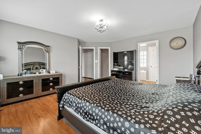 bedroom featuring ensuite bathroom, wood-type flooring, and a notable chandelier