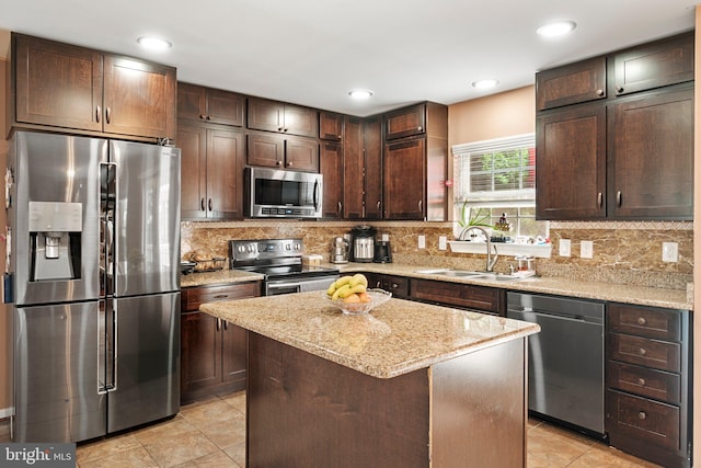 kitchen with dark brown cabinetry, sink, appliances with stainless steel finishes, backsplash, and a center island