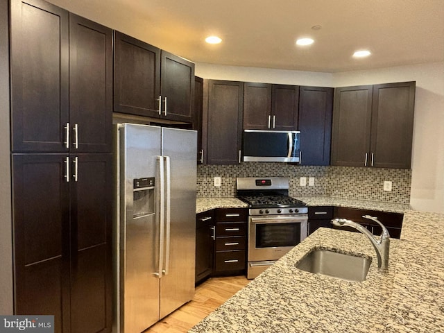 kitchen featuring light hardwood / wood-style floors, stainless steel appliances, light stone counters, sink, and dark brown cabinets