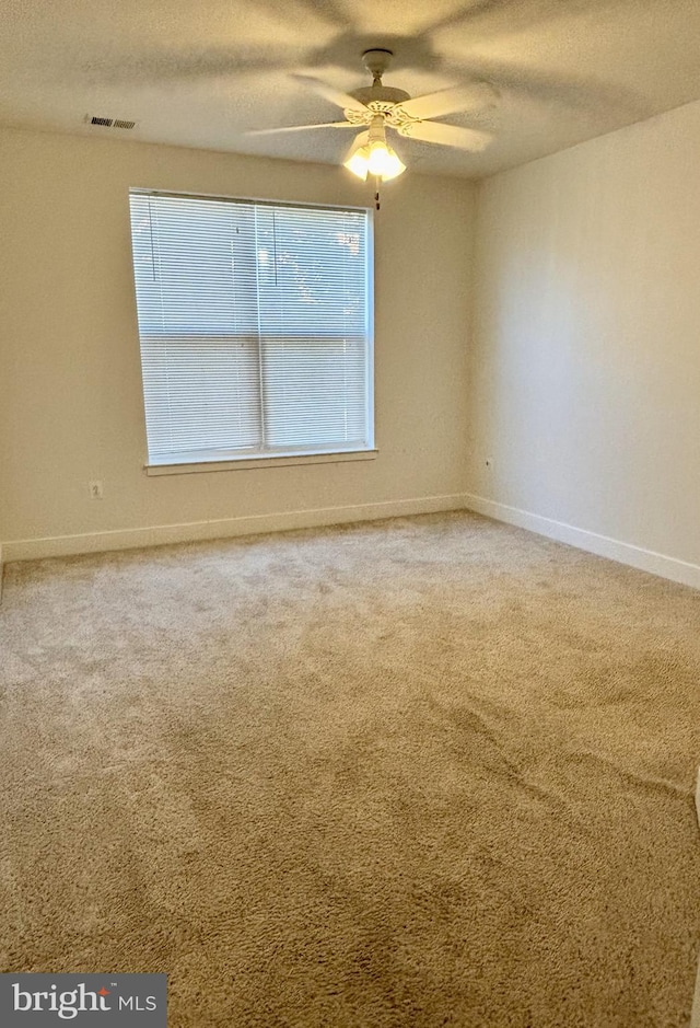 carpeted spare room with a textured ceiling and ceiling fan