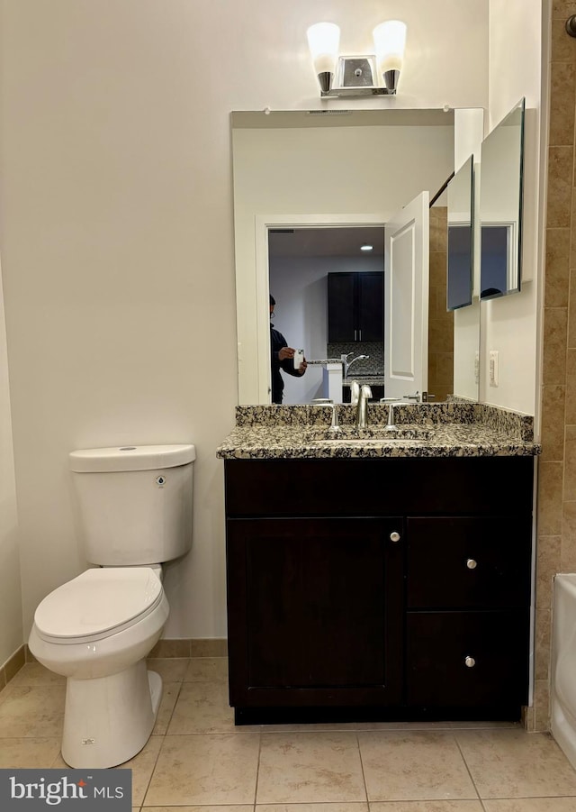 bathroom with toilet, vanity, and tile patterned floors