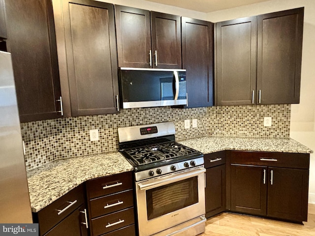 kitchen with light hardwood / wood-style floors, dark brown cabinets, and appliances with stainless steel finishes