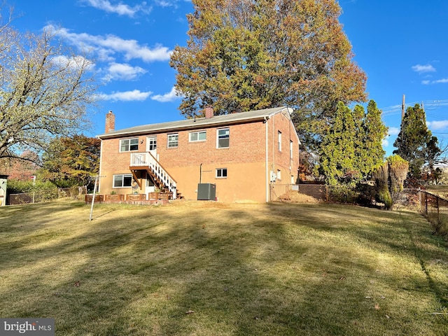 rear view of property with central AC unit and a yard