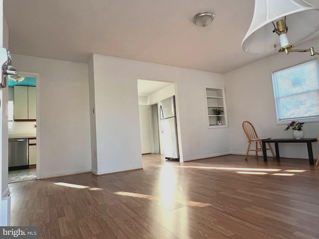 unfurnished living room featuring hardwood / wood-style floors and built in shelves