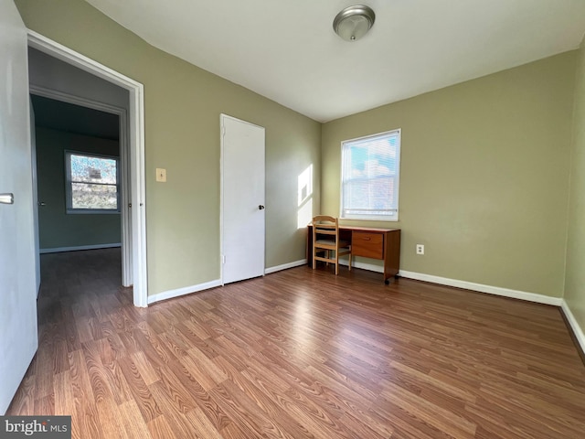 unfurnished bedroom with hardwood / wood-style flooring, multiple windows, and built in desk