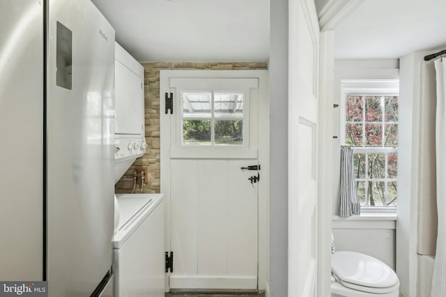 laundry room featuring stacked washer and clothes dryer and plenty of natural light