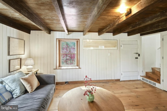 living room with wood walls, light wood-type flooring, wood ceiling, and beam ceiling