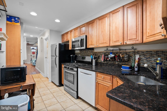 kitchen with light tile patterned flooring, sink, dark stone counters, ceiling fan, and stainless steel appliances