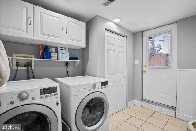 laundry area with cabinets, washing machine and dryer, and light tile patterned floors