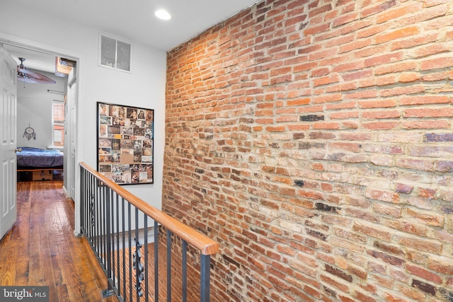 hall with dark hardwood / wood-style flooring and brick wall