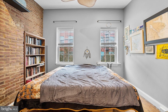 bedroom with wood-type flooring and brick wall