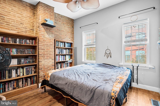 bedroom featuring brick wall and hardwood / wood-style floors