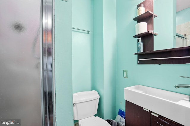 bathroom with a shower with door, vanity, and toilet