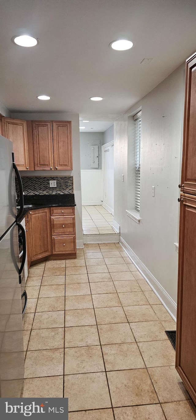 kitchen featuring light tile patterned floors, backsplash, and stainless steel refrigerator