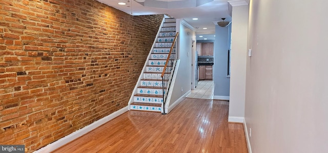 hallway with brick wall and light hardwood / wood-style flooring