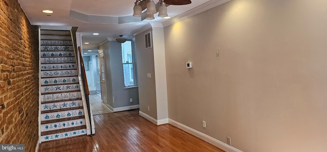 interior space featuring wood-type flooring, ornamental molding, and brick wall