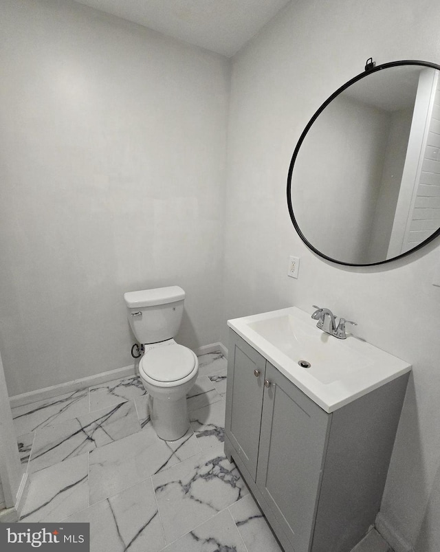 bathroom featuring toilet, baseboards, marble finish floor, and vanity