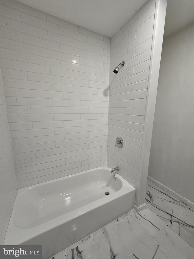 bathroom with bathtub / shower combination, marble finish floor, and baseboards